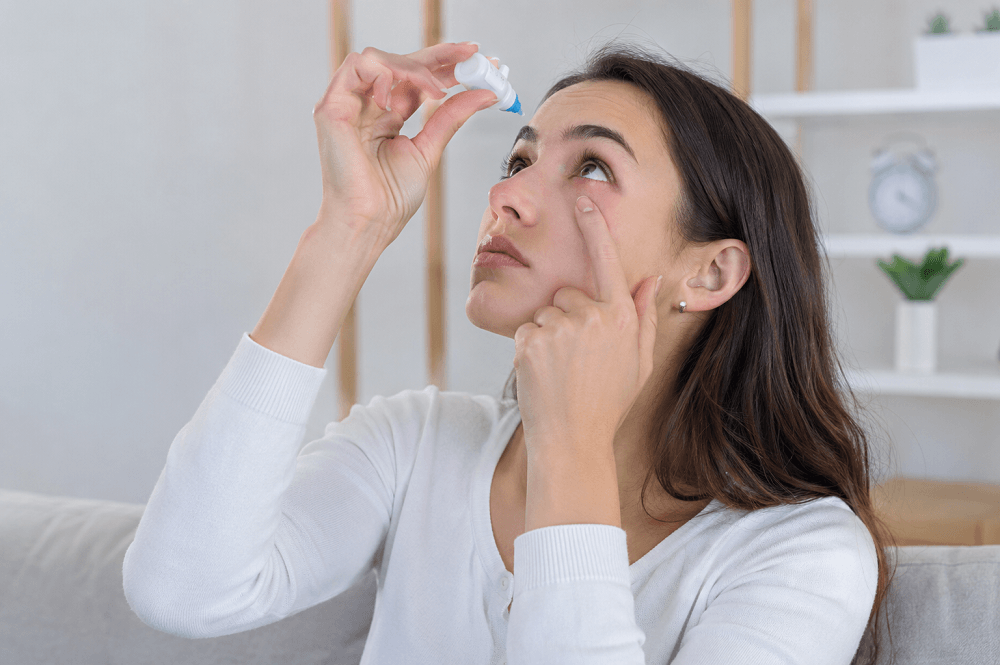 Woman applying lubricating eye drops to relieve dry eye symptoms