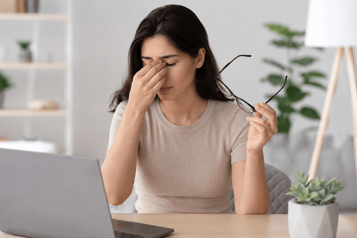 Woman experiencing dry eye symptoms while working on a laptop